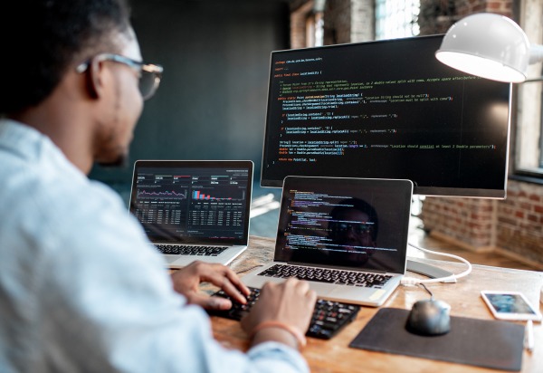 programmer writing code on computers at his desk